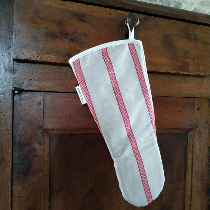Gauntlet long oven glove linen union with red stripes hanging off  the draw of a wooden cabinet