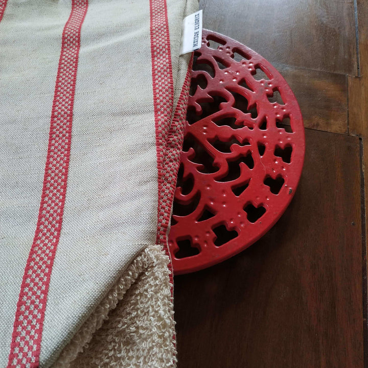 Cut image of Gauntlet long oven glove linen union with red stripes  on a red cast iron pot holder on a wooden table