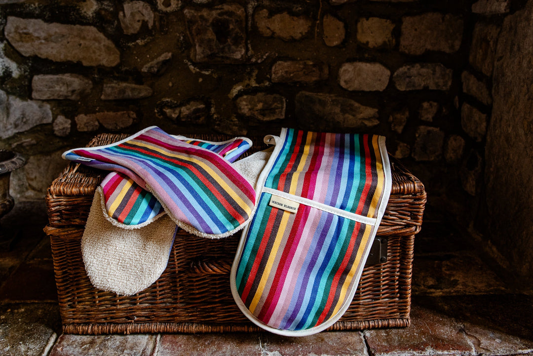 Rainbow woven oven gloves on a rustic basket— thoughtful gift for someone who loves cooking