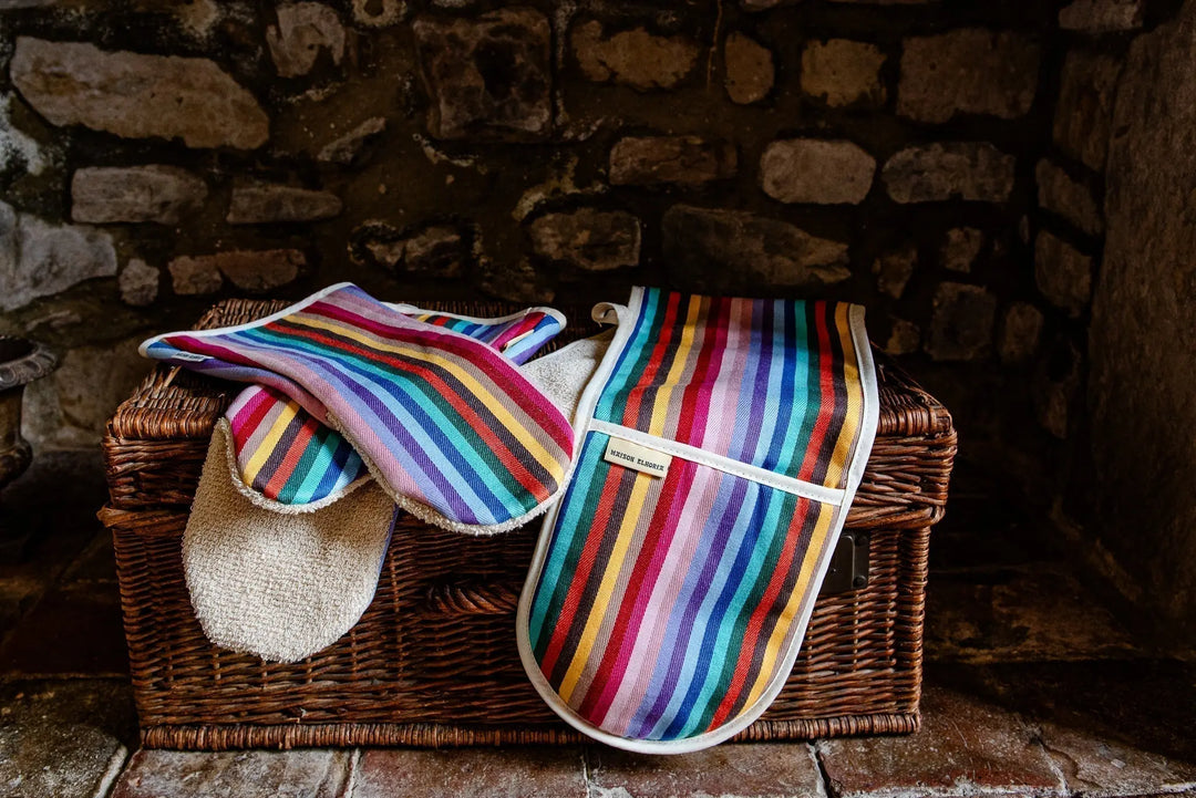 Double and Gauntlets long Rainbow oven gloves from Maisonelhoria.com  on a wicker basket trunk