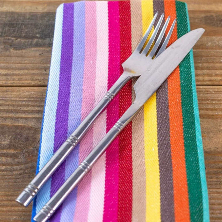 Rainbow napkin on wooden table with knife and fork on top