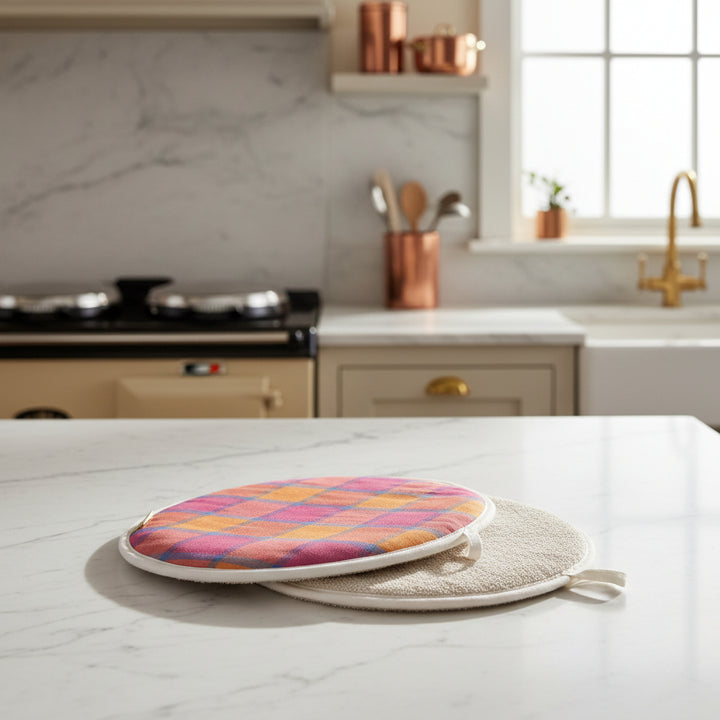 A pair of round chef  pads for Aga with plaid pattern orange pink blue and textured cover on a marble kitchen top