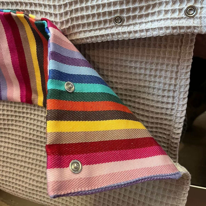 close up of a roller towel with poppers , rainbow header and waffle cotton beige fabric