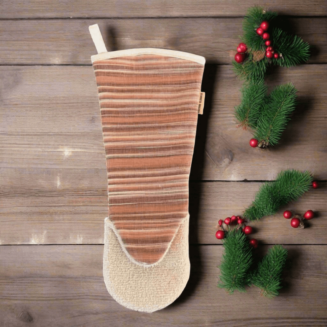 Oven glove gauntlet style long arm Red  on wooden background and a christmas pine branch with red Christmas bowls 
