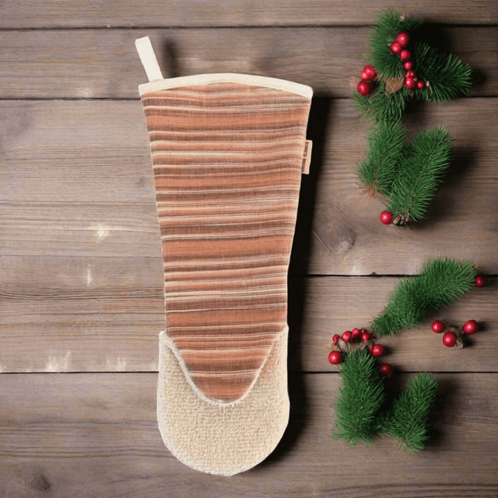 Oven glove gauntlet style long arm Red  on wooden background and a christmas pine branch with red Christmas bowls 