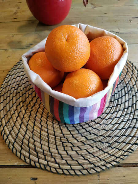 rainbow cotton storage bread bag on a table set holding oranges 