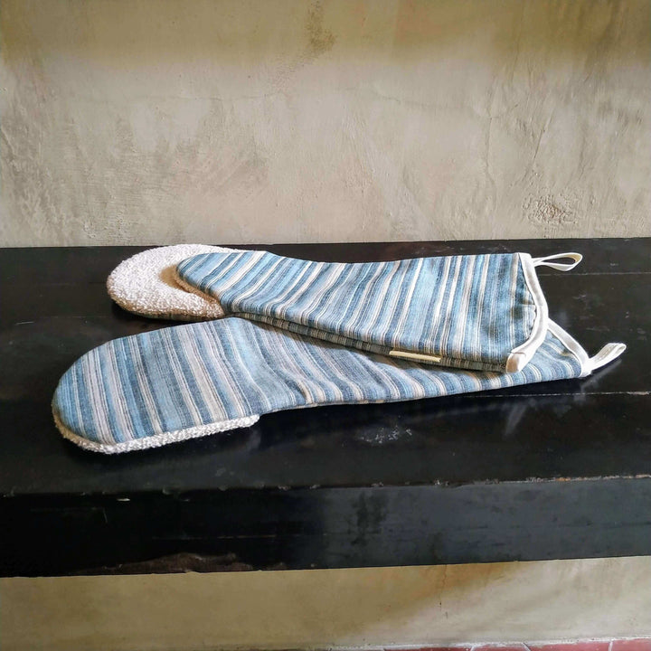 a pair of long gauntlet oven mitts on a black sideboard , close up with off white backdrop