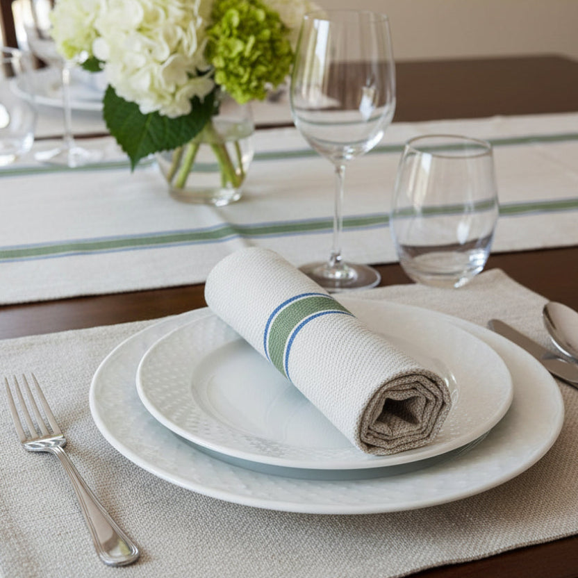 Table runner  with green and blue stripes on a table, with a matching napkin on the plate