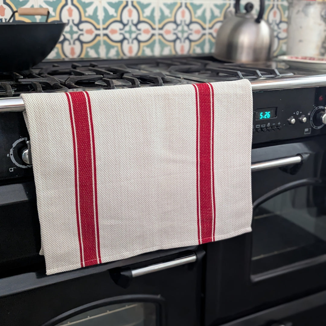 Kitchen stove with a red and white striped towel hanging on the handle, colorful tiled backsplash.