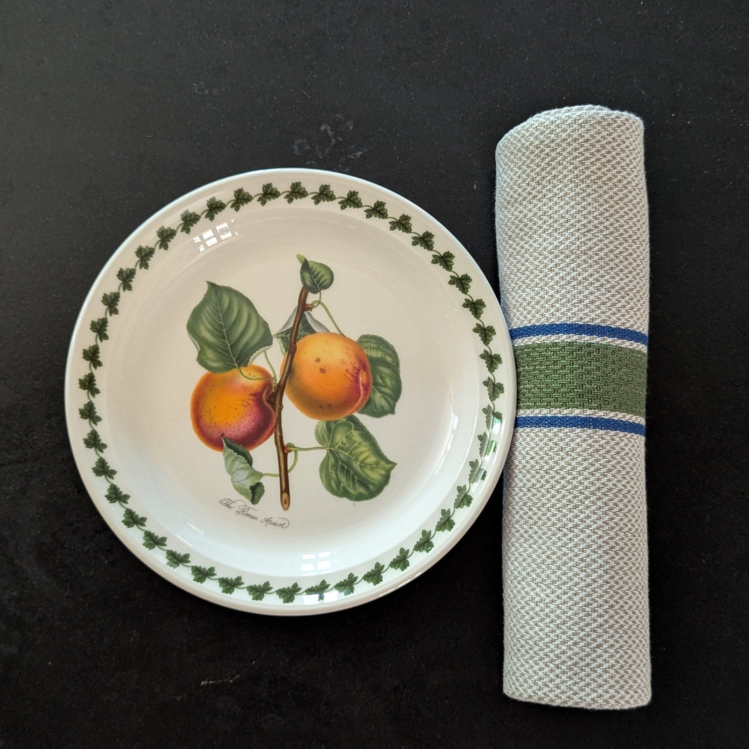 Decorative plate with fruit design and a striped rolled napkin on its side