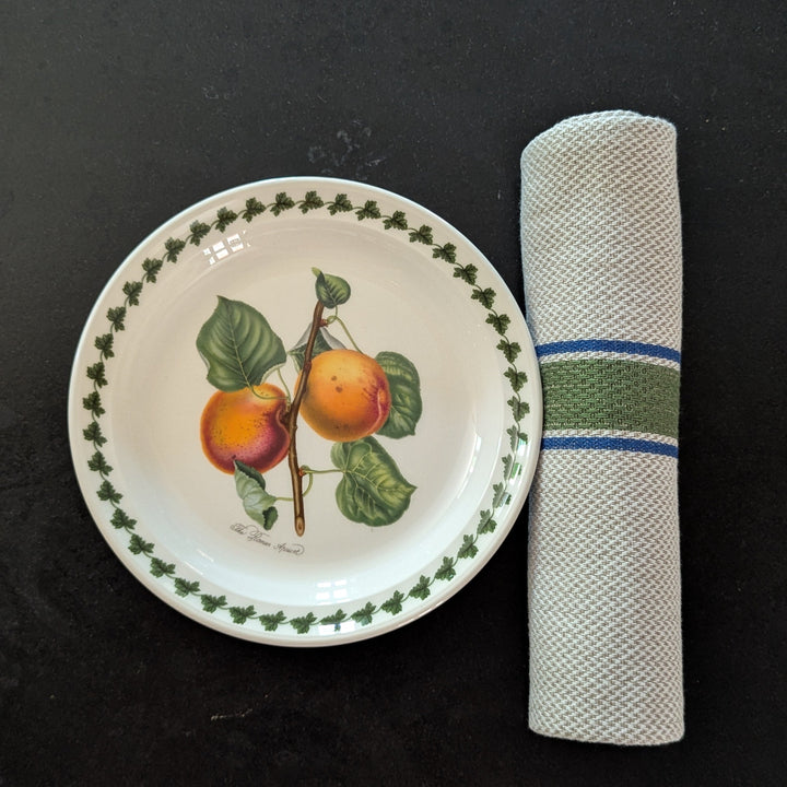 Decorative plate with fruit design and a striped rolled napkin on its side