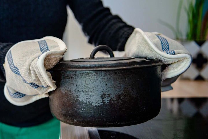 oven gloves holding a black pot close up