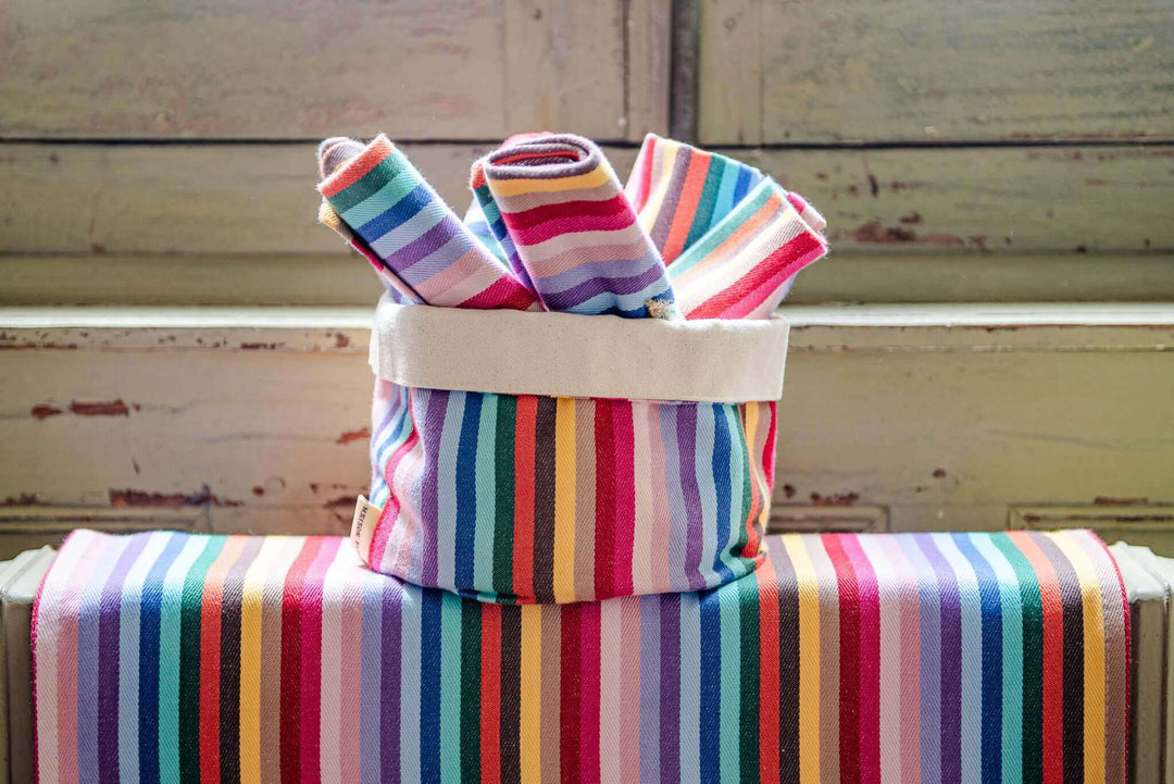 Rainbow napkins cotton rolled up on a rainbow pot bag by the base of a wooden window