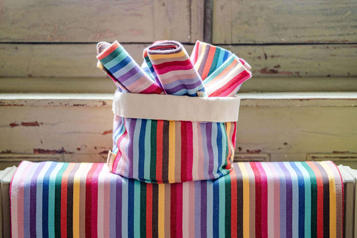 Rainbow napkins cotton rolled up on a rainbow pot bag by the base of a wooden window