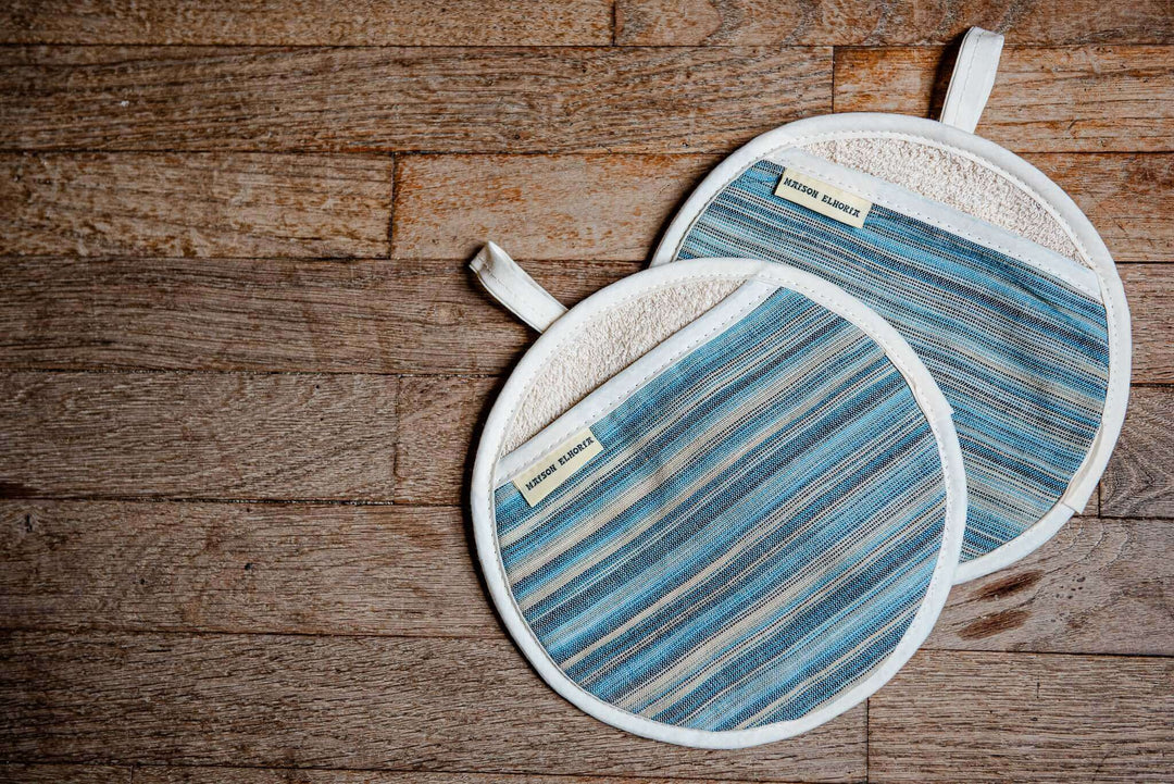 a pair of blue striped pot grabbers on a wooden background 
