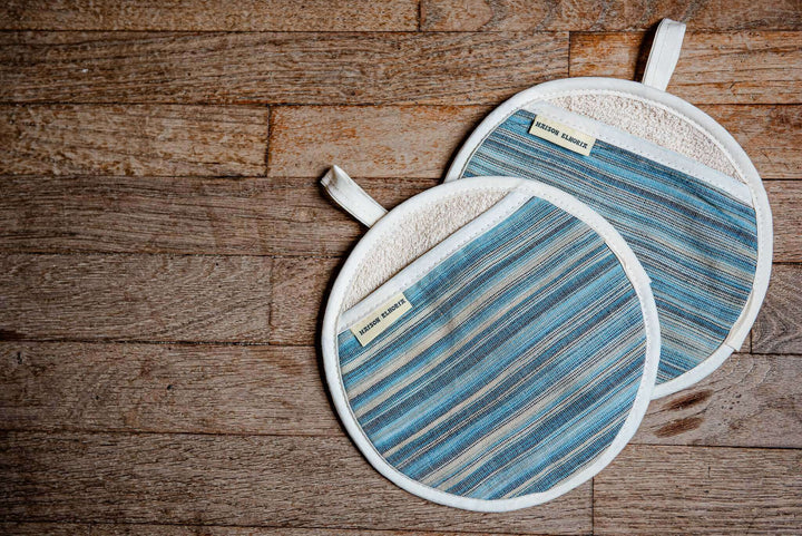 a pair of blue striped pot grabbers on a wooden background 
