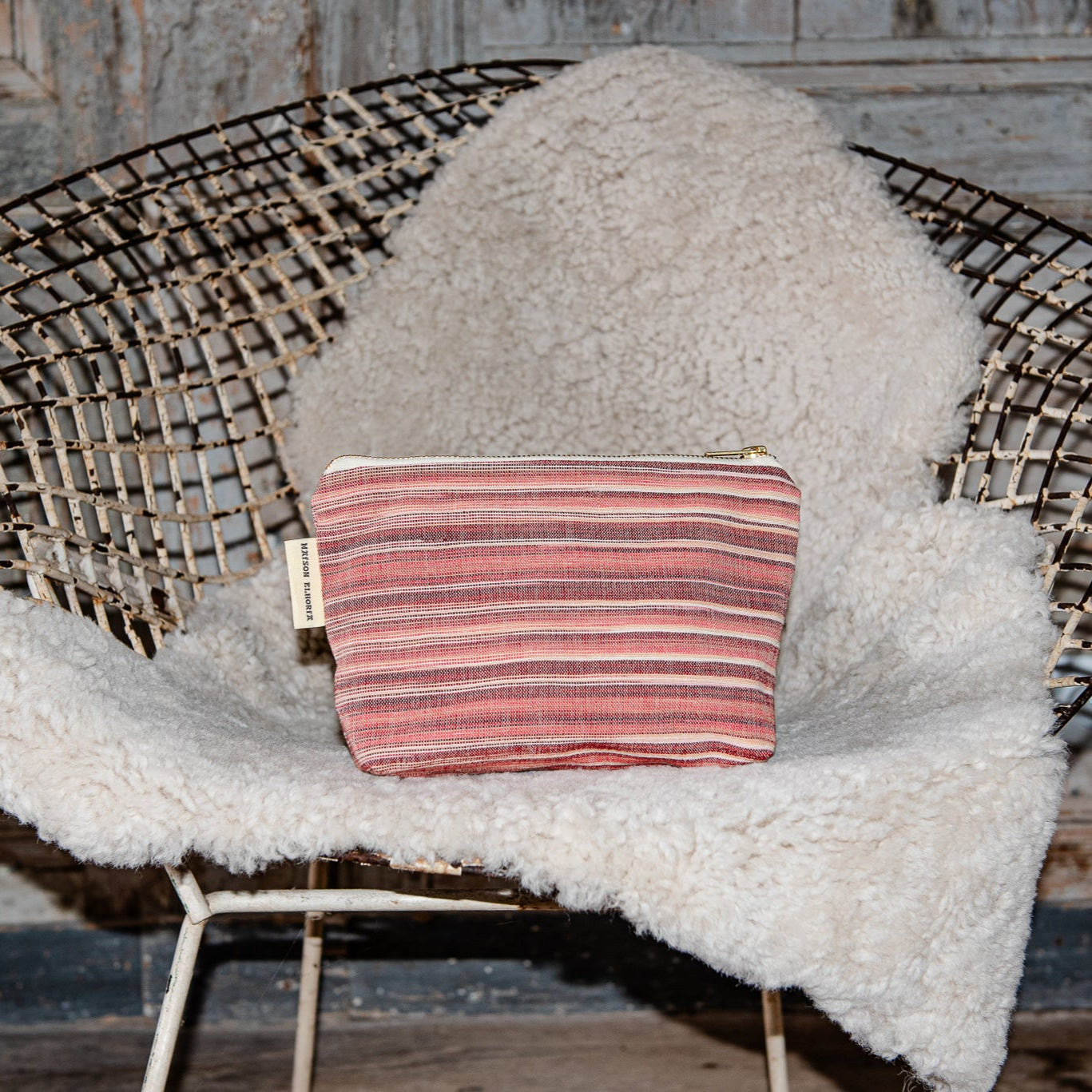 Red wash bag on a metal chair resting on a sheep skin