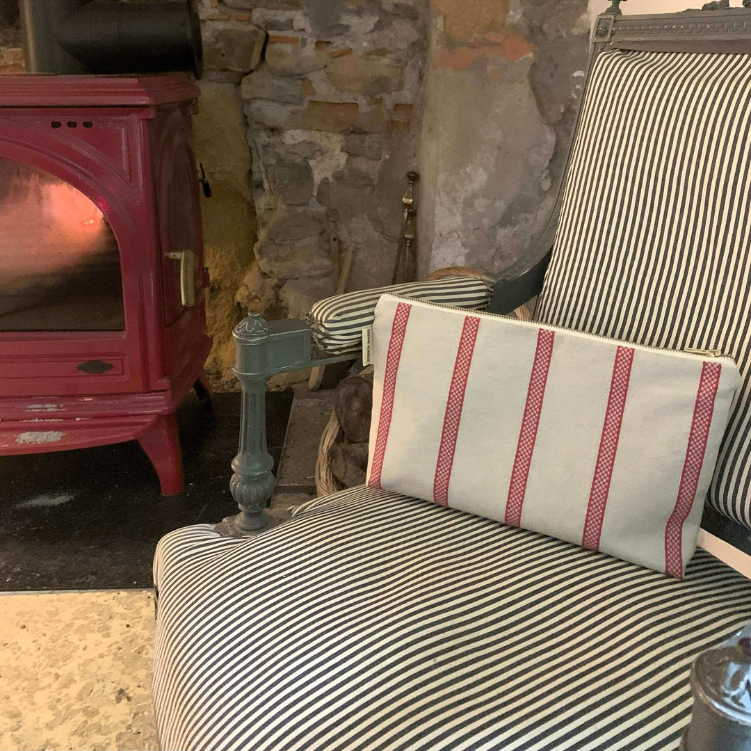 Red Striped linen toiletry bag on an armchair with a fire stove 