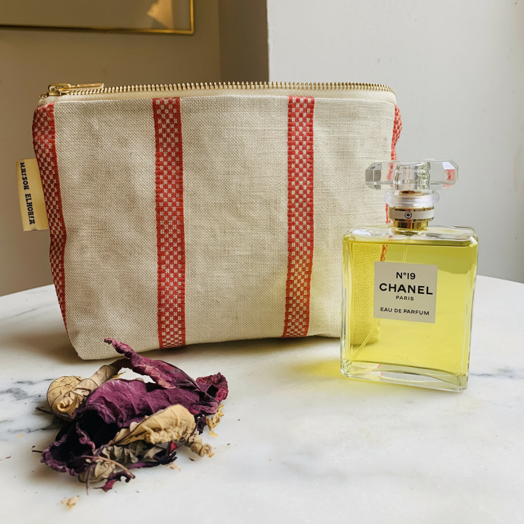 Chanel perfume bottle with a textured pouch on a marble surface
