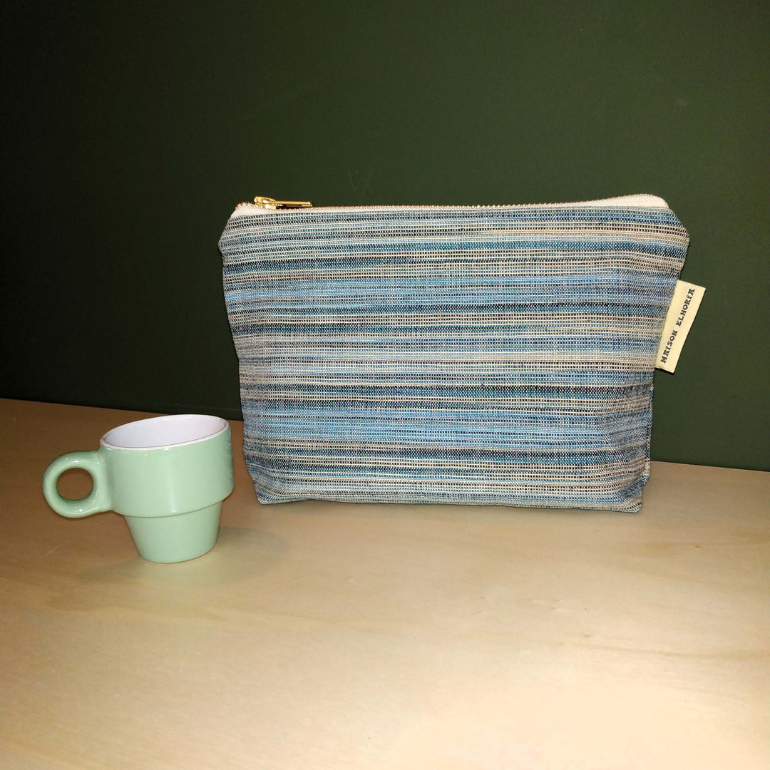Toiletry bag blue striped for men with an expresso green cup , light brown worktop and green backdrop