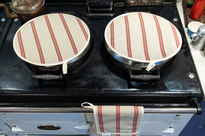 A pair of smart Linen union with Red stripes insulating Aga hob plate covers, with matching oven double oven glove partly showing, on a pale blue Aga range cooker, seen from above