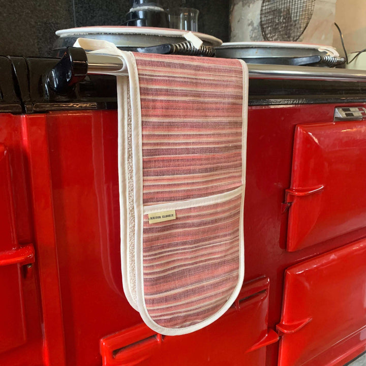 Red striped double oven gloves hanging off a red Aga range cooker 
