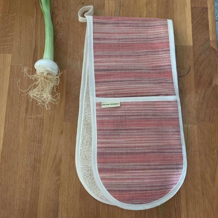 Red striped oven glove on wooden worktop with a spring onion on the top left