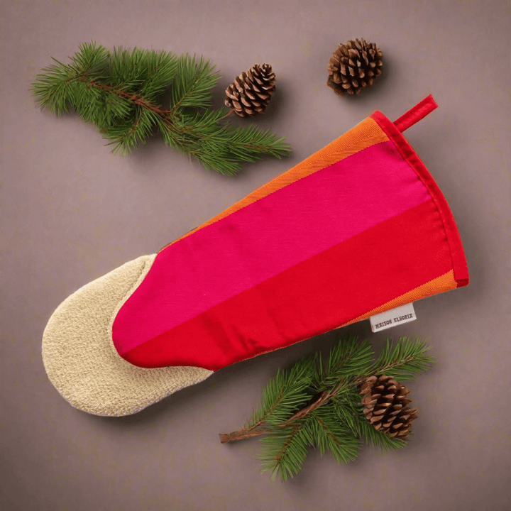 Gauntlet long oven glove red orange pink  with old pink background and pine tree cones and branches