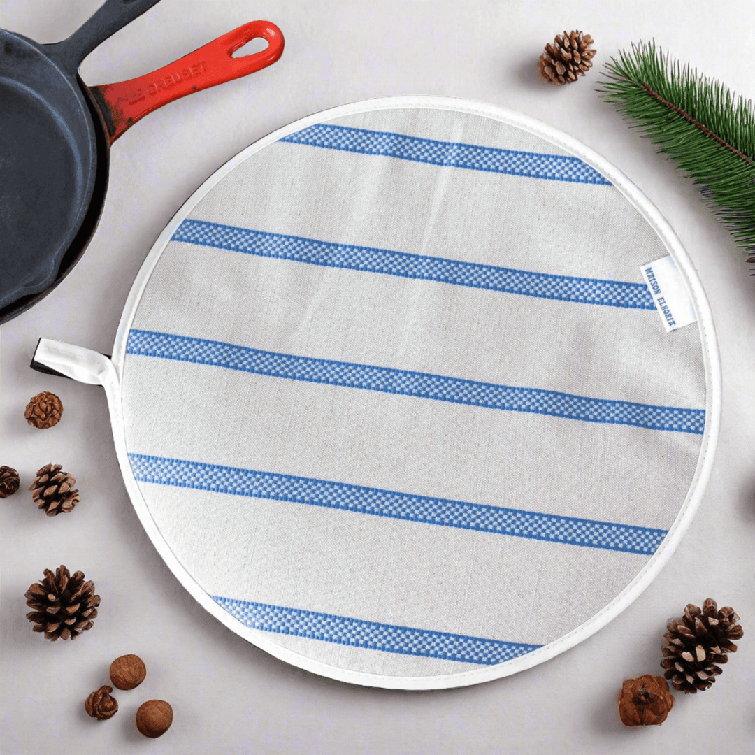 Aga lid cover linen union with blue stripes with a partial view of cooking accessories around it view from above
