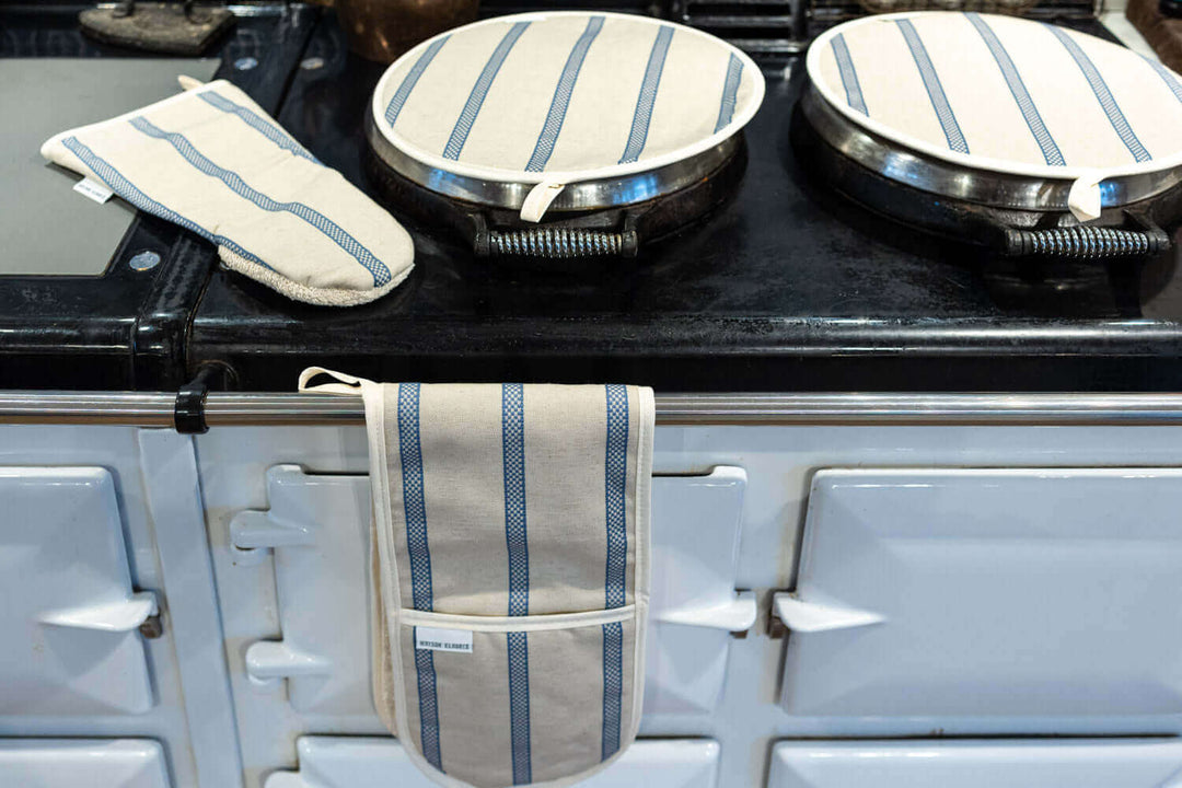 A pair of smart Linen union with Red stripes insulating Aga hob plate covers, with matching oven double oven glove and Gauntlet oven glove , on a pale blue Aga range cooker, seen from above in a angle 