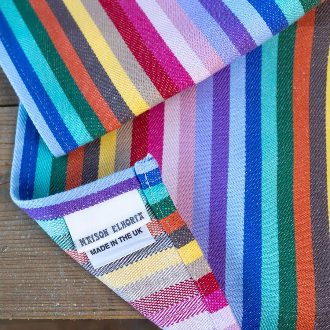 Tea Towel Rainbow woven cotton herringbone close up, with focus on corner  corner showing the label Maison Elhoria made in the UK