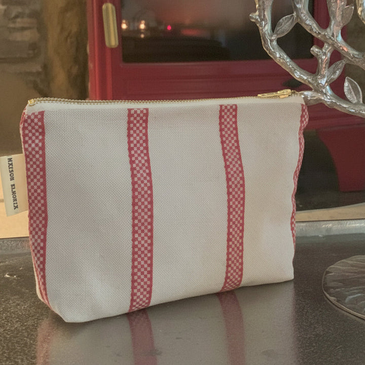 Makeup bag linen union with red stripes with a red wood burner in the background
