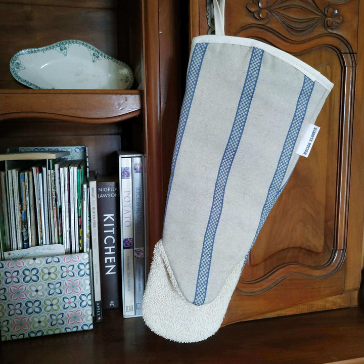 Gauntlet long oven glove red orange pink organic cotton hanging off a wooden dresser with cooking books and an antique dish