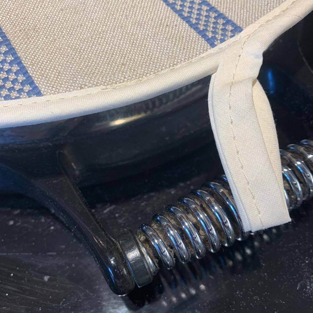 Small end piece with loop of Linen union with blue stripes insulating Aga hob plate cover on Aga 